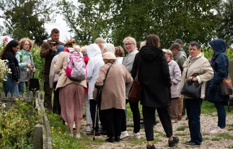 Widzimy plecy grupy ludzi ubranych w kurtki. Na przeciw tej grupy stoi młody mężczyzna, a obok niego dwie kobiety.